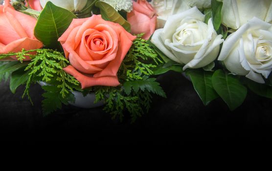 still life decorated orange and white roses with various leaves on dark tone wooden background
