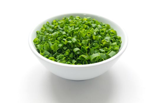 Cut tube chive leaves in white bowl, isolated background