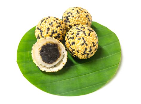 deep fried sticky rice balls with black and white sesame, preserved jujube center filled on round shape banana leaf