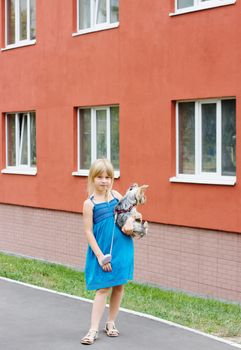 Girl 5 years with Yorkshire terrier in her arms near a high-rise building