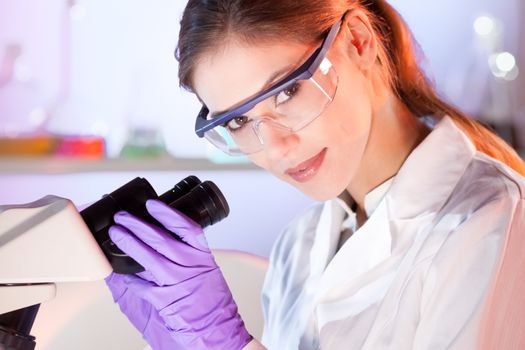 Life scientist researching in laboratory. Portrait of a attractive, young, confident female health care professional microscoping in hes working environment. Healthcare and biotechnology.