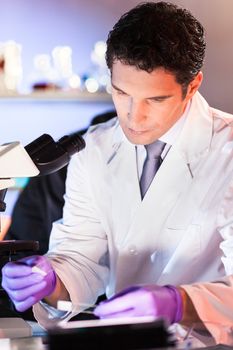 Life scientist researching in laboratory. Attractive young male scientist looking at the microscope slides in laboratory. Healthcare and biotechnology concept.