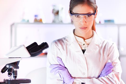 Portrait of a attractive, young, confident female health care professional with microscope in hes working environment. Healthcare and biotechnology.