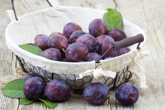 fresh plums in a basket on wooden background