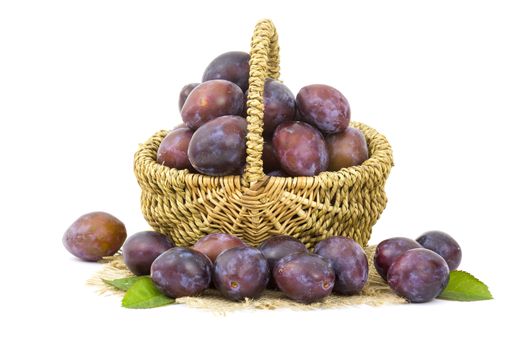 fresh plums in a basket on white background