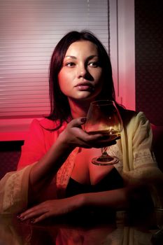 beautiful girl with glass of brandy in cafe