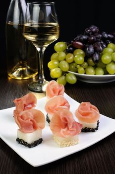 Appetizer of melon cubes in sesame with a slice of gammon