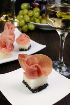 Appetizer of melon cubes in sesame with a slice of gammon