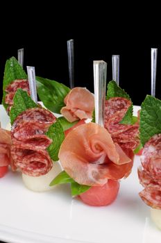 Canape of watermelon balls with a melon with gammon and salami