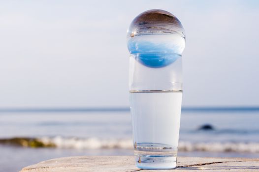 Crystal ball in a glass with water on the seacoast