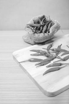 red chili peppers on cutting board over wood table background black and white tone color style