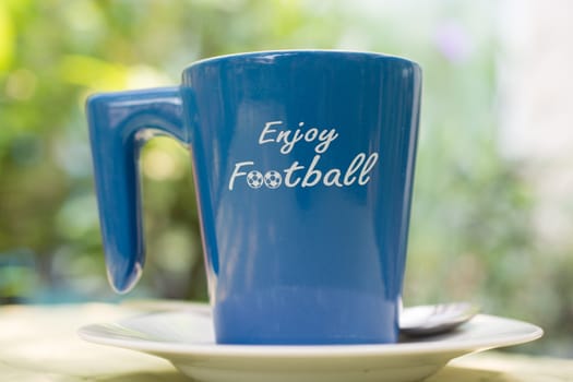 Coffee cup with the word enjoy football on its side.