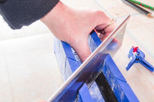Hand of a worker with miter saw against a bright background.