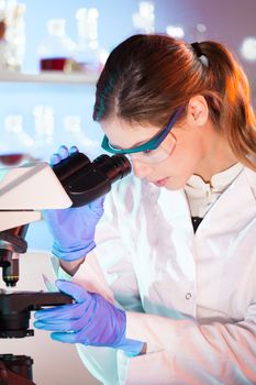 Life scientist researching in laboratory. Portrait of a attractive, young, confident female health care professional microscoping in hes working environment. Healthcare and biotechnology.