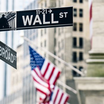 View of Wall street sign in New York with New York Stock Exchange background