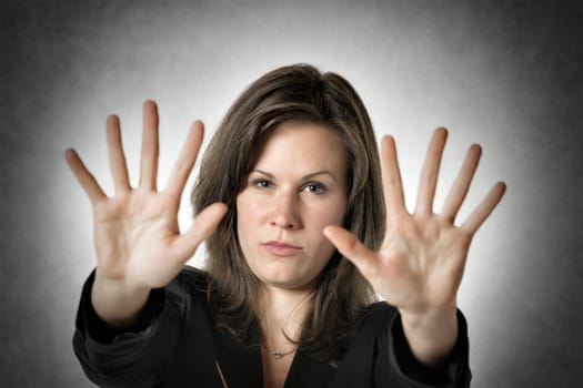 Business woman in black suit holds both hand up to stop someone or something