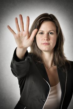 Business woman in black suit holds her right hand up to stop someone or something