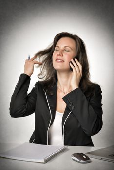 Businesswoman sitting at the desk and on the phone with her smartphone