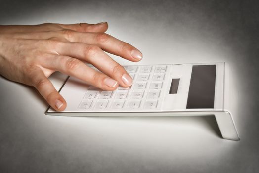 Closeup of hand of business woman typing on a calculator with free space on the display