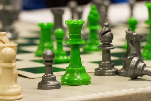 a green queen stands off the chess board observing the ensuing battle