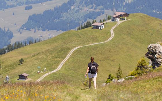 Hiker, young woman with backpack walking on footpath, Switzerland