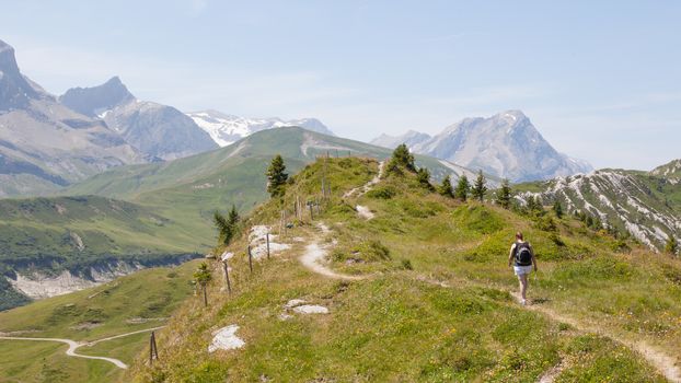 Hiker, young woman with backpack walking on footpath, Switzerland