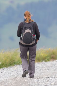 Hiker, young woman with backpack walking on footpath, Switzerland