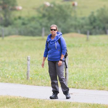 Hiker, young woman with backpack walking on footpath, Switzerland