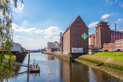 Bremen, Germany - June 6, 2014: Anabranch of Weser river with old brick buildings in Bremen-Walle in the west of the city - farina producer Rolandmuehle on the right