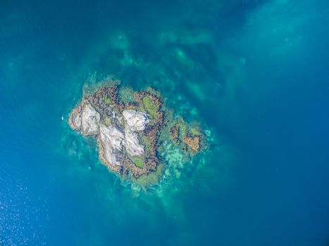Scenic aerial view of tiny rocky islet in turquoise sea