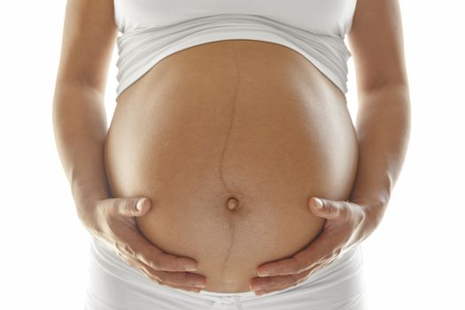 Last trimester pregnant woman holding her belly over a white background.