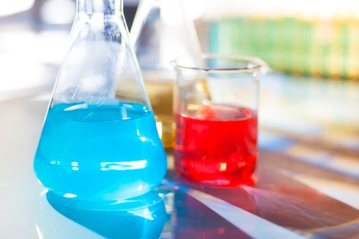 Backlit laboratory test flask containing colorful liquids.