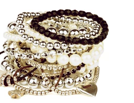 Pile of Various Pearl, Silver and Black Jewelry Gems Bracelets closeup on white background. Retro Styled