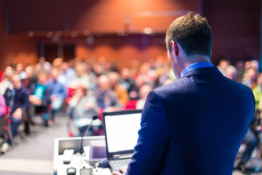 Speaker at Business Conference with Public Presentations. Audience at the conference hall. Entrepreneurship club. Rear view. Horisontal composition. Background blur.