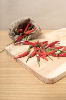 red chili peppers on cutting board over wood table background