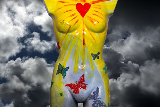front of a multi colored artistic painted female mannequin torso with cloud background and clipping path