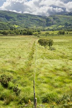 view from a beautiful hiking route the kerry way in ireland of fence leading to rocky mountains