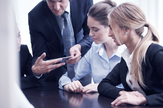 businessman showing his mobile phone to his coworkers