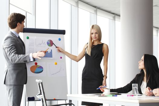 Workers at business meeting looking at presentation of financial reports in modern office