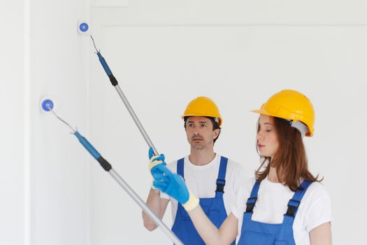 two workmen painting white wall