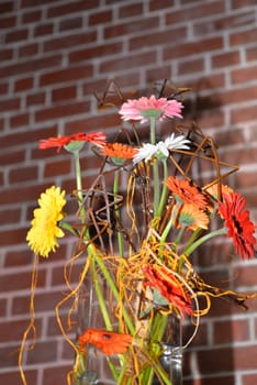 flowers in a vase against a brick wall