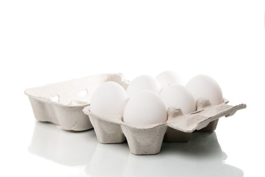 Six white chicken eggs in an egg box