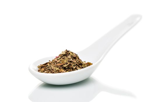 Basil (Ocimum basilicum) spice on a white porcelain spoon