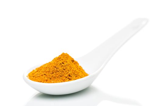 Curry powder spice on a white porcelain spoon