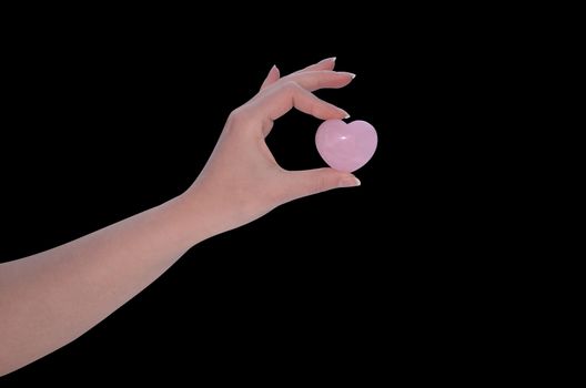 Hand holding Rose Quartz heart isolated on black background
