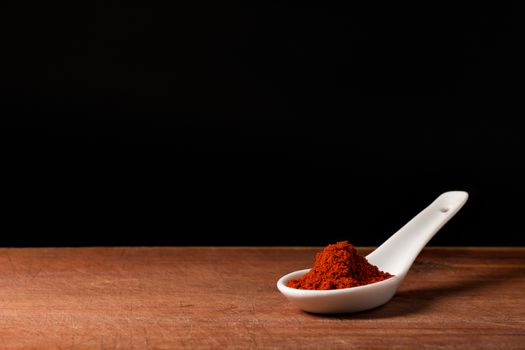 Paprika powder threads on a white porcelain spoon