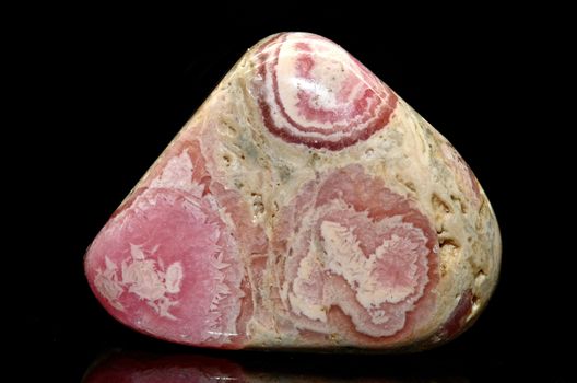 Sample of a beautiful Rhodochrosite tumbled specimen on black background