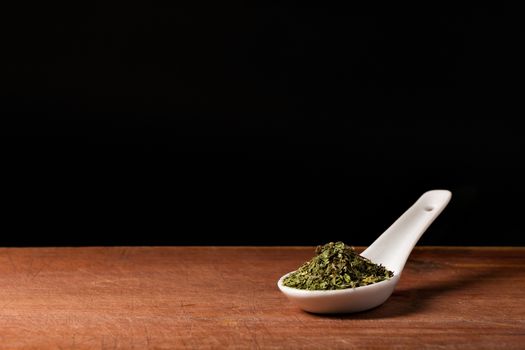 Basil (Ocimum basilicum) threads on a white porcelain spoon