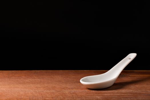  white porcelain spoon on wodden plank