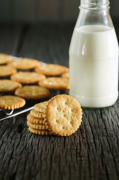 Delicious biscuits with milk on a wooden table.